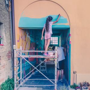 Bambina su ponteggio che dipinge una parete, laboratorio artistico espressivo