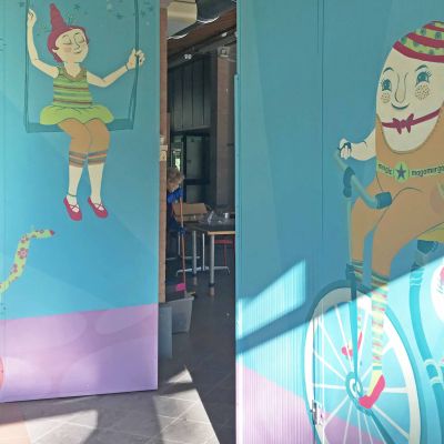 MagoMargo dalle scarpette magenta sulla bicicletta con un gatto, porta le stelle con la bacchetta magica, dipinto su parete con colori dalle tonalità vintage