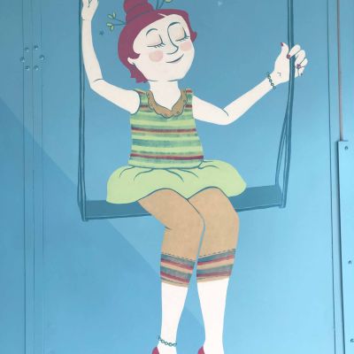 Olga la Trapezista dalle scarpette e dai capelli magenta che sorride sul trapezio, dipinto su parete con colori dalle tonalità vintage