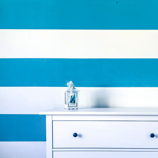 Dipinto murale a tema marittimo per cameretta bimbo, righe turchese su fondo bianco e mobile bianco