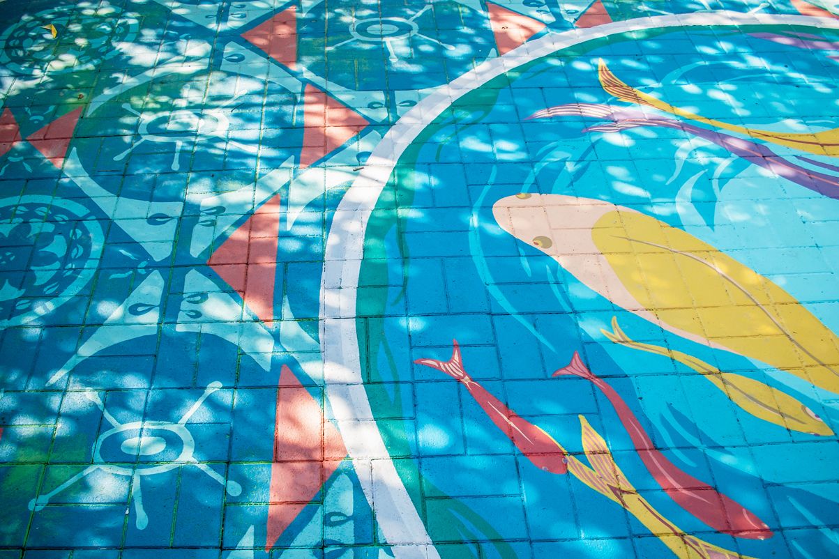 Decorazione eseguta a mano su pavimentazione esterna, fiori e pesci nell'acqua, dipinti a pennello