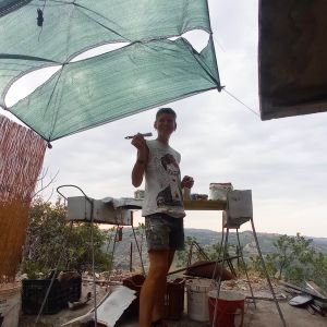 Donna con pennallo in mano nel cantiere del murales che sta dipingendo