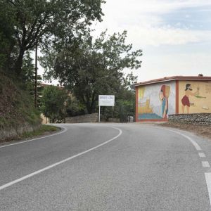 Strada su una piazza panoramica sullo sfondo un edifcio basso, sulle pareti è dipinto un murale dai colori vivaci